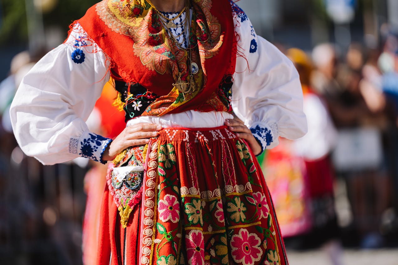 Colorful traditional dress worn during an outdoor cultural festival with focus on intricate embroidery.